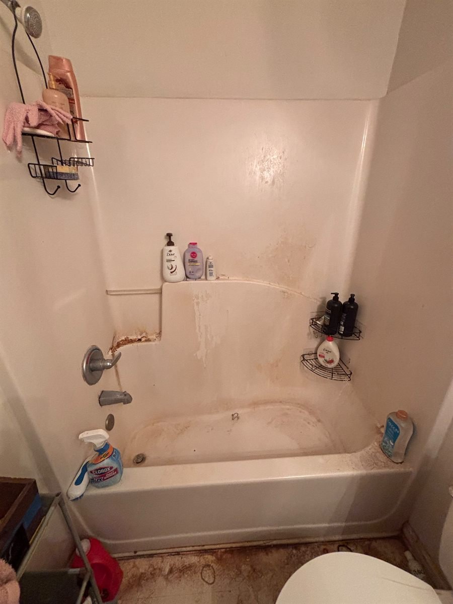 Before: bathtub with soap scum, rust stains and clutter